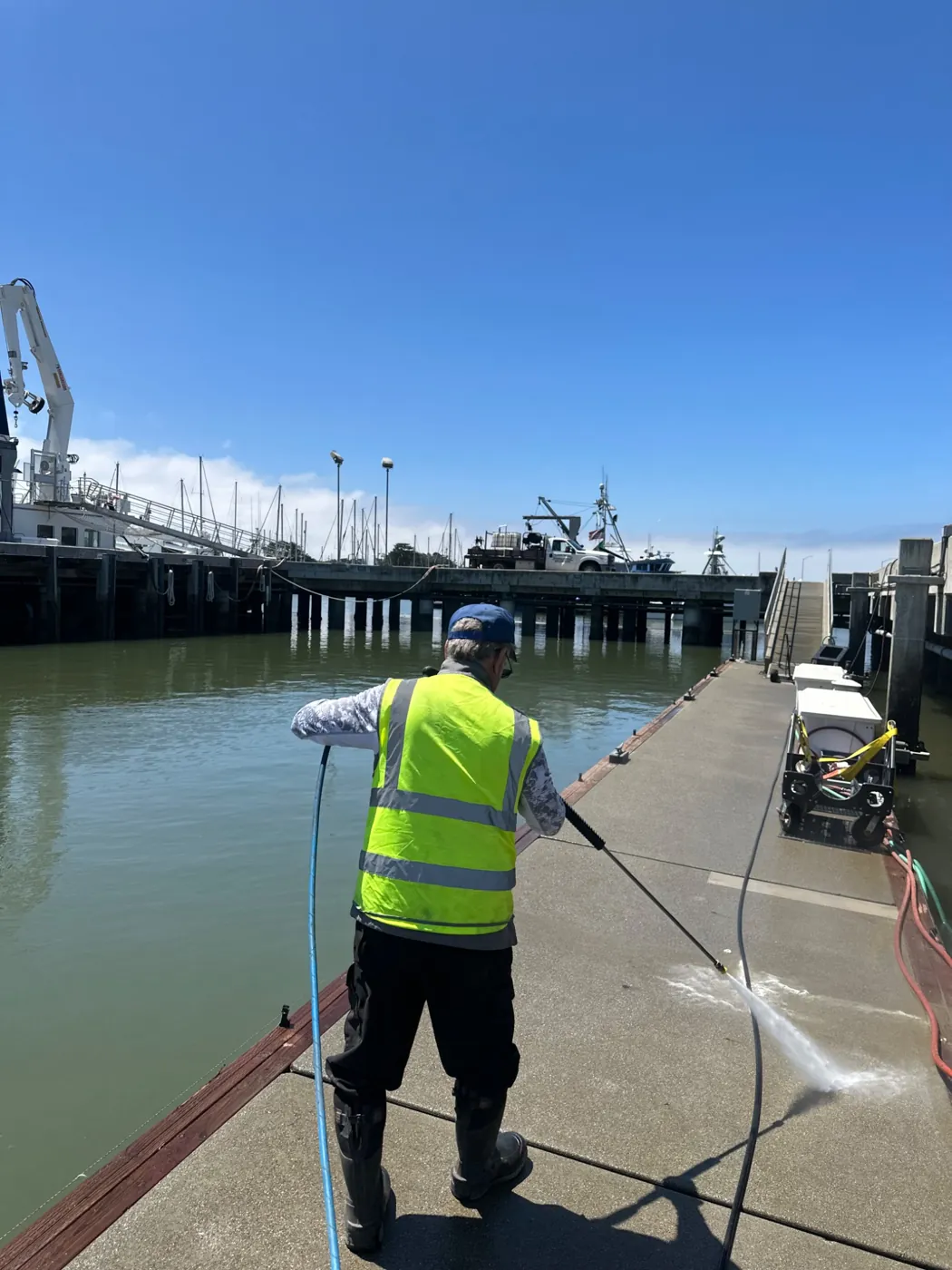 Team member pressure washing a waterfront walkway